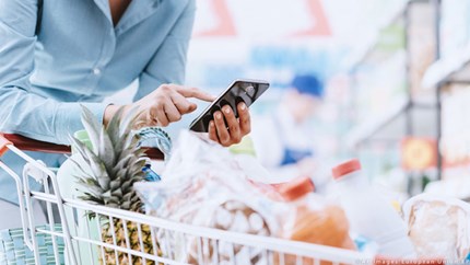 Donna che usa lo smartphone al supermercato